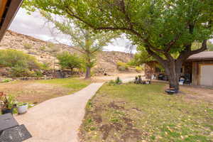 View of grassy yard with a deck with mountain view