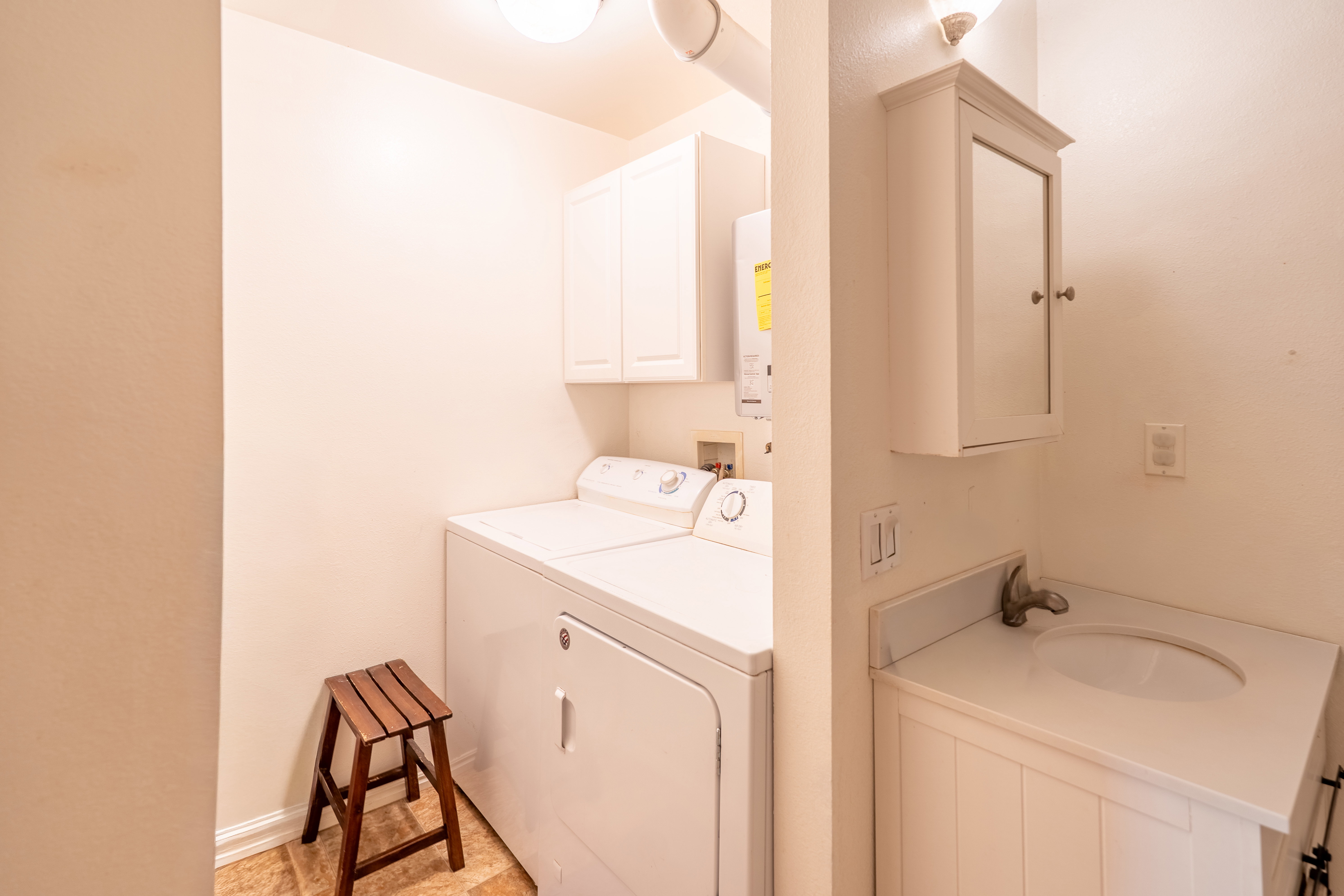 Laundry area with separate washer and dryer, cabinet space, and water heater