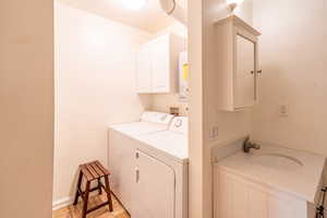 Laundry area with separate washer and dryer, cabinet space, and water heater