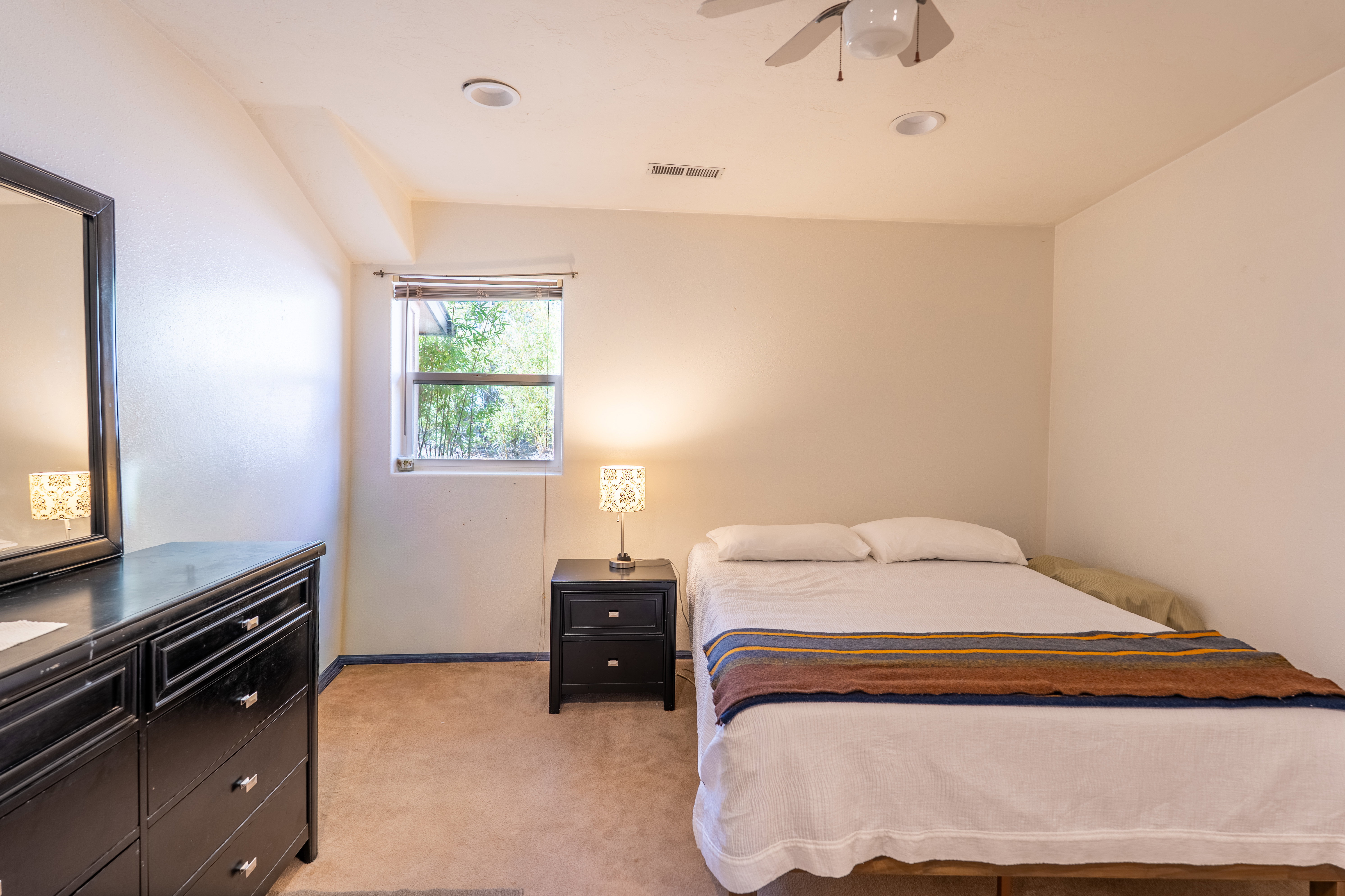 Bedroom featuring light carpet, ceiling fan, and vaulted ceiling