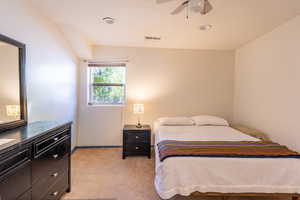 Bedroom featuring light carpet, ceiling fan, and vaulted ceiling