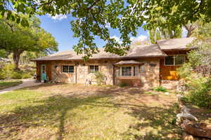 View of front of home featuring stone siding, a shingled roof, and a front yard