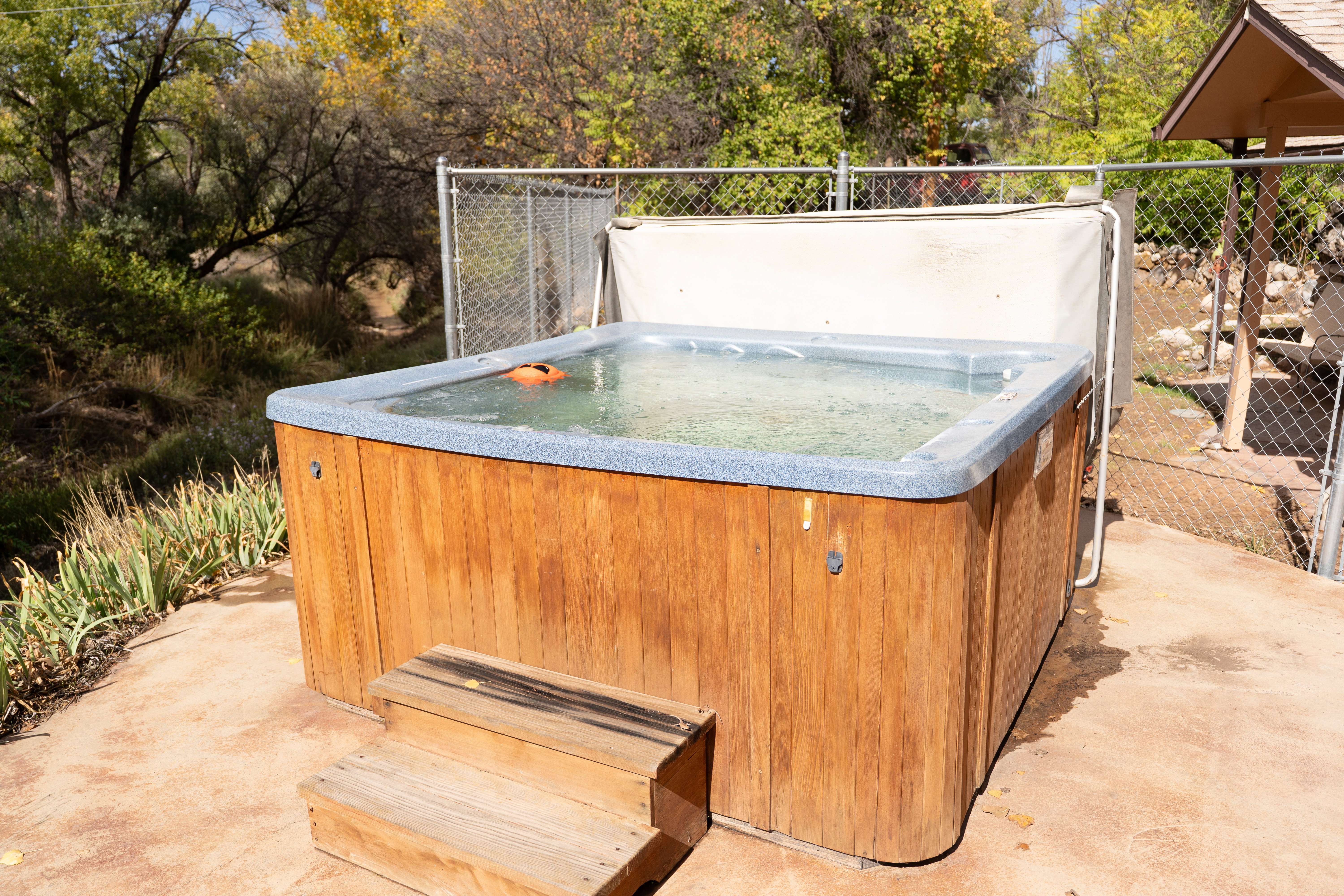 View of patio / terrace with a hot tub and view of wooded area