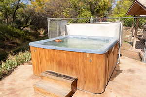 View of patio / terrace with a hot tub and view of wooded area