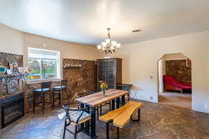 Dining area with stone flooring, a fireplace, a chandelier, and arched walkways