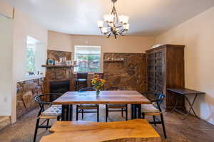 Dining area featuring stone tile floors, a fireplace, and a chandelier