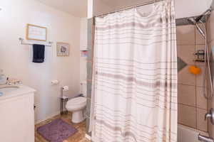 Full bath with shower / tub combo with curtain, vanity, and light tile patterned floors