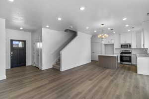 Kitchen featuring open floor plan, white cabinetry, appliances with stainless steel finishes, recessed lighting, and a chandelier
