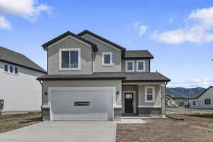 View of front of house featuring covered porch, driveway, stucco siding, brick siding, and an attached garage