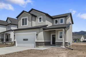 View of front of house with an attached garage, stucco siding, concrete driveway, and brick siding