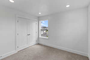 Unfurnished bedroom with carpet flooring, a closet, and recessed lighting