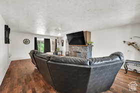 Living area with a fireplace, dark wood-style floors, and a textured ceiling