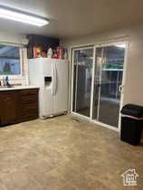 Kitchen with white fridge with ice dispenser, light countertops, and dark brown cabinetry