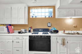 Kitchen with white cabinetry, light countertops, and white appliances