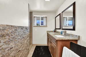 Full bath with light tile patterned floors, double vanity, tile walls, and a tile shower
