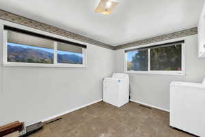 Laundry room featuring independent washer and dryer, cabinet space, a mountain view, and stone finish flooring