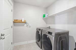 Washroom with washer and dryer and light tile patterned floors