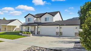 View of front of home with driveway, stone siding, covered porch, a shingled roof, and an attached garage