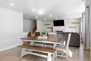Dining room with light wood-style floors, a fireplace, stairway, and recessed lighting