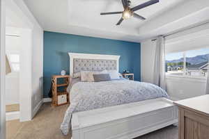 Bedroom featuring a tray ceiling, a mountain view, a ceiling fan, and carpet floors