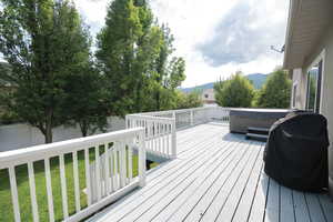 Deck featuring a fenced backyard, a mountain view, area for grilling, and a hot tub
