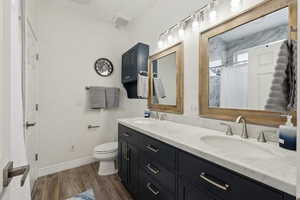 Full bathroom with double vanity, dark wood finished floors, and curtained shower