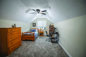 Bedroom with carpet floors, a textured ceiling, lofted ceiling, and ceiling fan