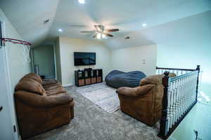 Carpeted living area featuring a textured ceiling, lofted ceiling, and a ceiling fan