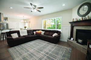 Living area with a textured ceiling, dark wood finished floors, recessed lighting, ceiling fan, and a tiled fireplace