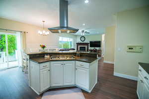 Kitchen with white cabinets, extractor fan, a fireplace, a textured ceiling, and dark wood-style floors