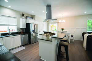 Kitchen with island range hood, white cabinetry, a center island, a breakfast bar area, and recessed lighting