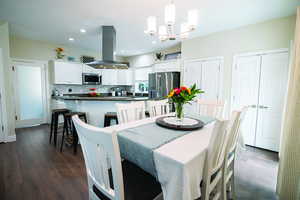 Dining room with dark wood-type flooring, a chandelier, and recessed lighting