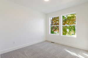 Carpeted spare room featuring baseboards