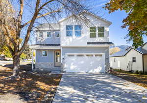 View of front of property with stone siding, covered porch, driveway, and an attached garage