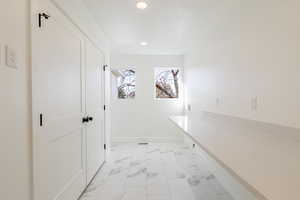 Corridor with light marble finish floors and recessed lighting