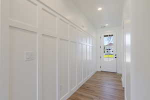 Doorway featuring recessed lighting, wood finished floors, and a decorative wall