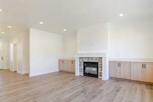 Unfurnished living room featuring recessed lighting, a stone fireplace, and light wood-style flooring