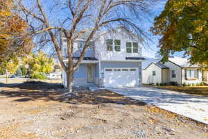 Traditional-style house with driveway, stone siding, an attached garage, and covered porch