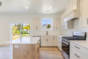 Kitchen featuring appliances with stainless steel finishes, light wood-style floors, recessed lighting, a kitchen island, and white cabinetry