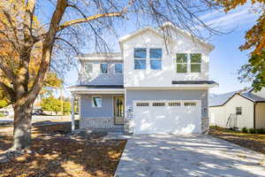 View of front of house featuring stone siding, a porch, concrete driveway, and an attached garage