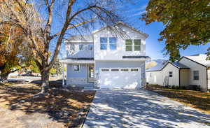 Traditional-style home featuring driveway, stone siding, an attached garage, and a porch