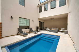 View of swimming pool featuring an outdoor living space with a fire pit, a patio area, a swimming pool, and a ceiling fan