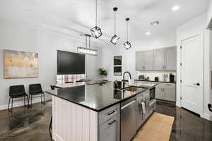Kitchen with gray cabinets, a center island with sink, tasteful backsplash, hanging light fixtures, and stainless steel dishwasher