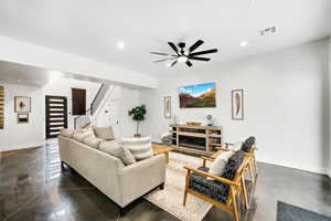 Living area featuring a ceiling fan, recessed lighting, stairway, and concrete flooring