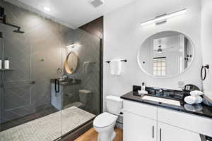 Full bathroom featuring vanity, a stall shower, a ceiling fan, and wood finished floors