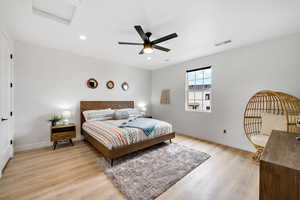 Bedroom with light wood-type flooring, a ceiling fan, attic access, and recessed lighting