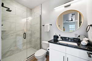 Bathroom featuring a shower stall, vanity, and a ceiling fan
