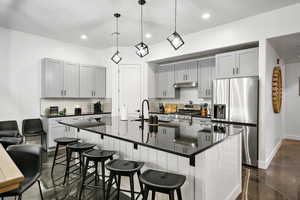 Kitchen with appliances with stainless steel finishes, a large island, decorative backsplash, a kitchen bar, and recessed lighting