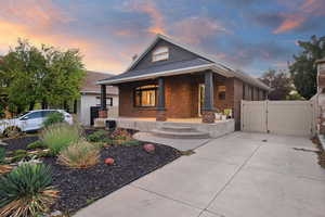 Bungalow-style house featuring a gate, brick siding, and a porch