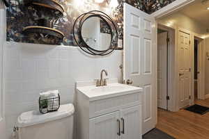 Bathroom with vanity, tile walls, wallpapered walls, and wood finished floors